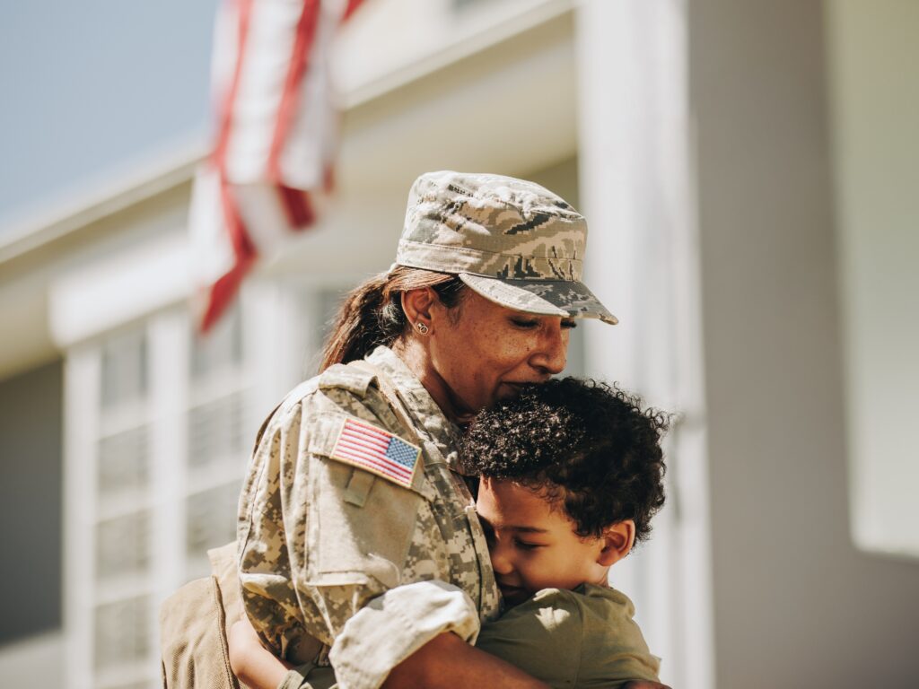 A female military member hugs a young boy.